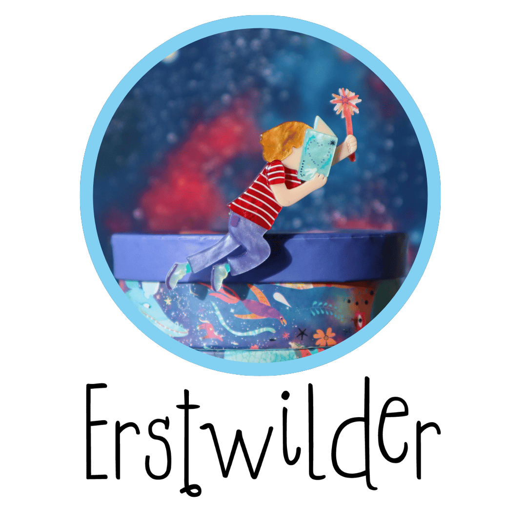 The close up photo of a small brooch which is a child in profile covering their face with an open book, their other hand outstretched holding a wand. The Erstwilder logo is below it.