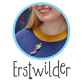 A close up of the top shoulder of a woman wearing a brooch which is a child in profile covering their face with an open book, their other hand outstretched holding a wand. The Erstwilder logo is below the photo.